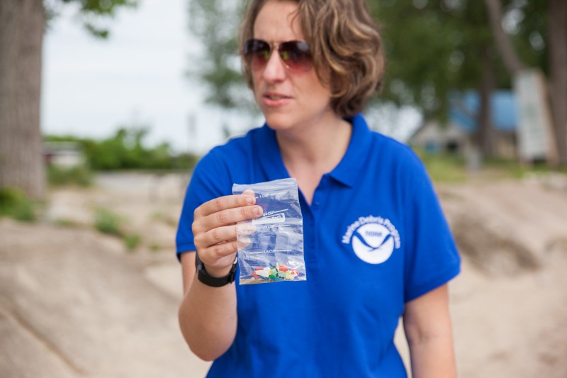 A woman holding a bag of microplastics.