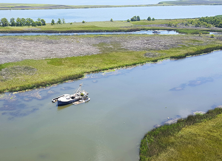 Aerial view of abandoned vessels with osprey nest on mast, located in Florida waterway.