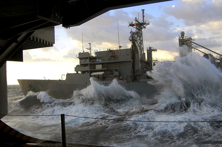 Rough seas pound the hull of support ship USNS Arctic as it sails alongside aircraft carrier USS Harry S. Truman.