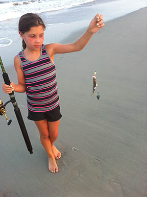 A young girl goes surf fishing with her father in the early evening. (NOAA)<br />
    </div>