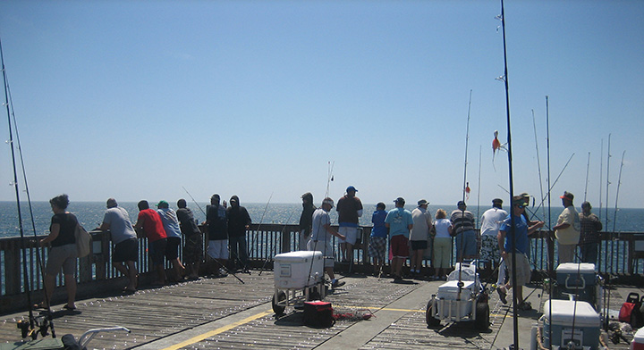 People standing around a pier fishing.