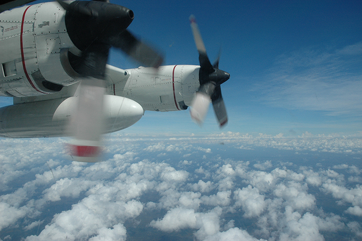 Looking out of an observer window on a Coast Guard C-130 airplane over the ocean.