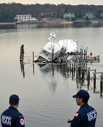 Coast Guard responders oversee a partially submerged vessel in Navesink River, N.J., Nov. 10, 2012. Boom was placed around the vessel to mitigate pollution during the response efforts.