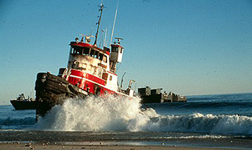 The tug Scandia aground on a beach in the pounding surf.