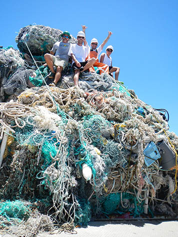 NOAA collected nearly 50 metric tons of marine debris, shown here with researchers sitting on top of the piles of nets aboard the ship Oscar Elton Sette. NOAA collected nearly 50 metric tons of marine debris, piled on ship's deck.