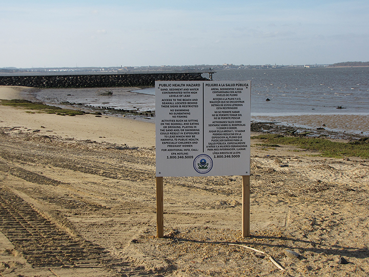 Public health hazard sign about lead contamination on a beach and jetty.