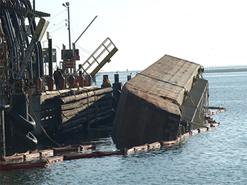 Barge NMS 1477 tilted on its side at a Texas City dock.