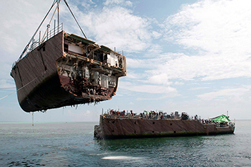 A crane vessel removes the bow of the mine countermeasure ship Ex-Guardian.