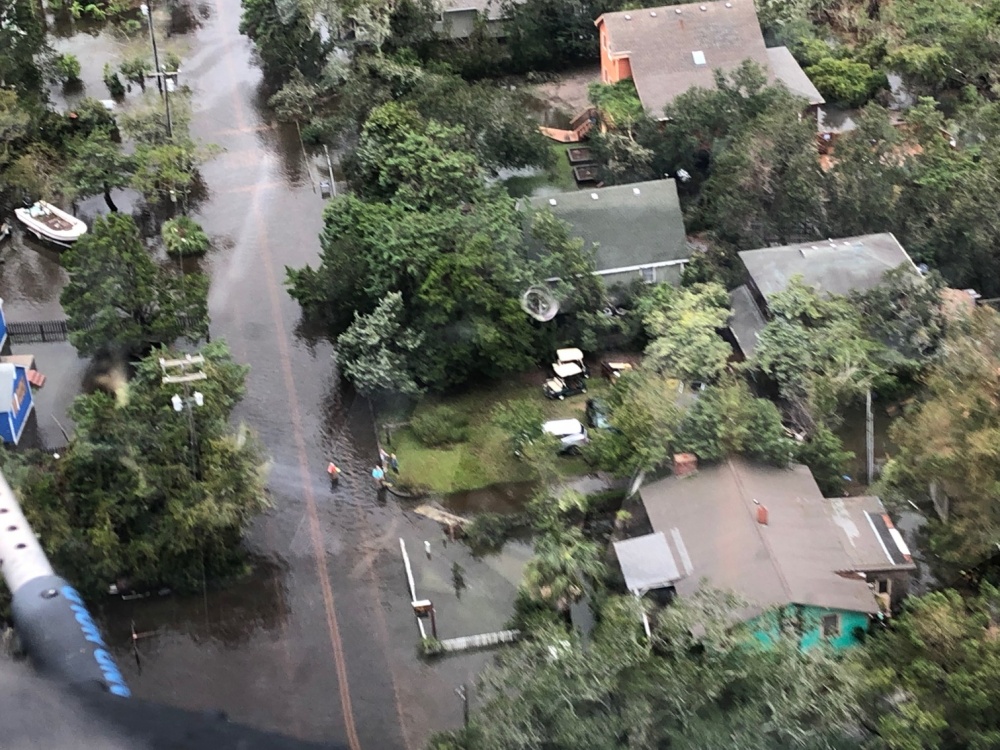 An aerial image of a flooded residential area with oil sheens visible in the water.