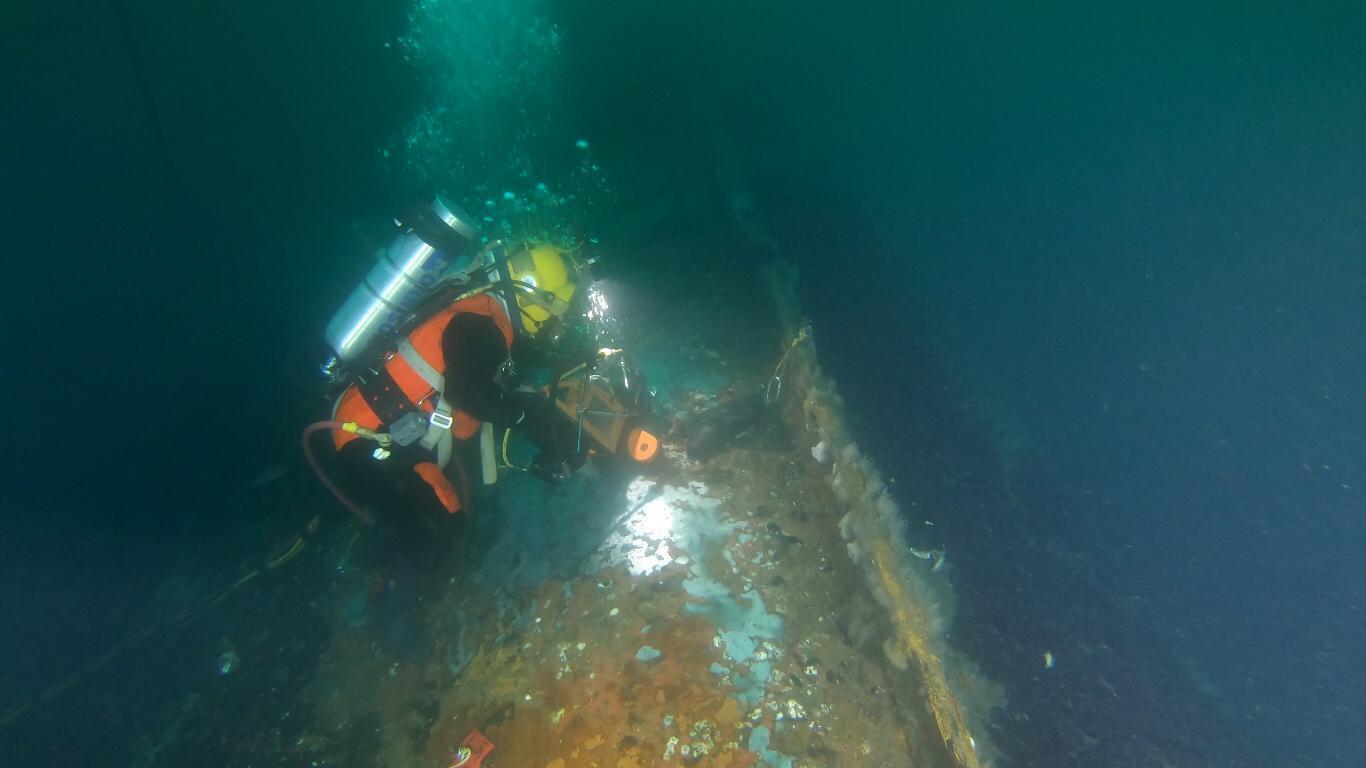 A diver working on a sunken vessel on the seafloor.