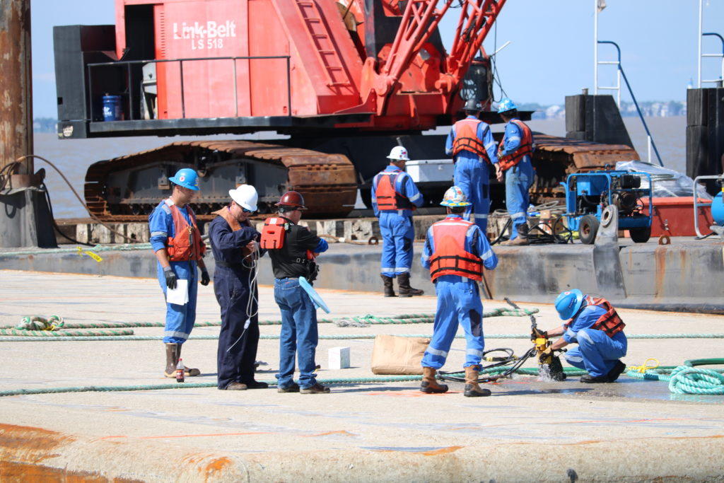 A crew of people in blue response gear with hard hats and life jackets. 