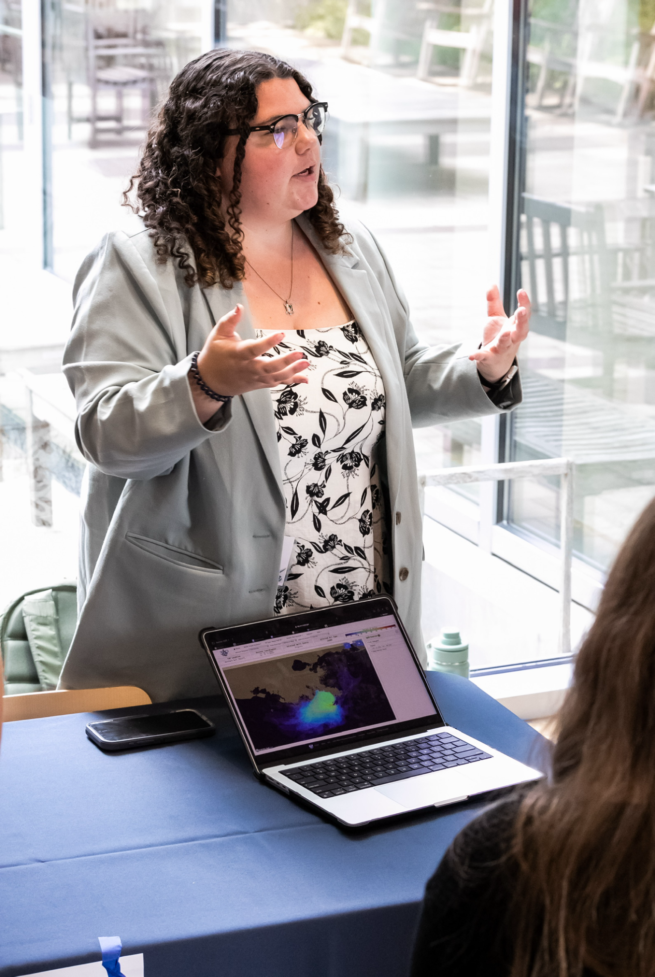 Student presents behind a table with a laptop opened to a mapping software program.