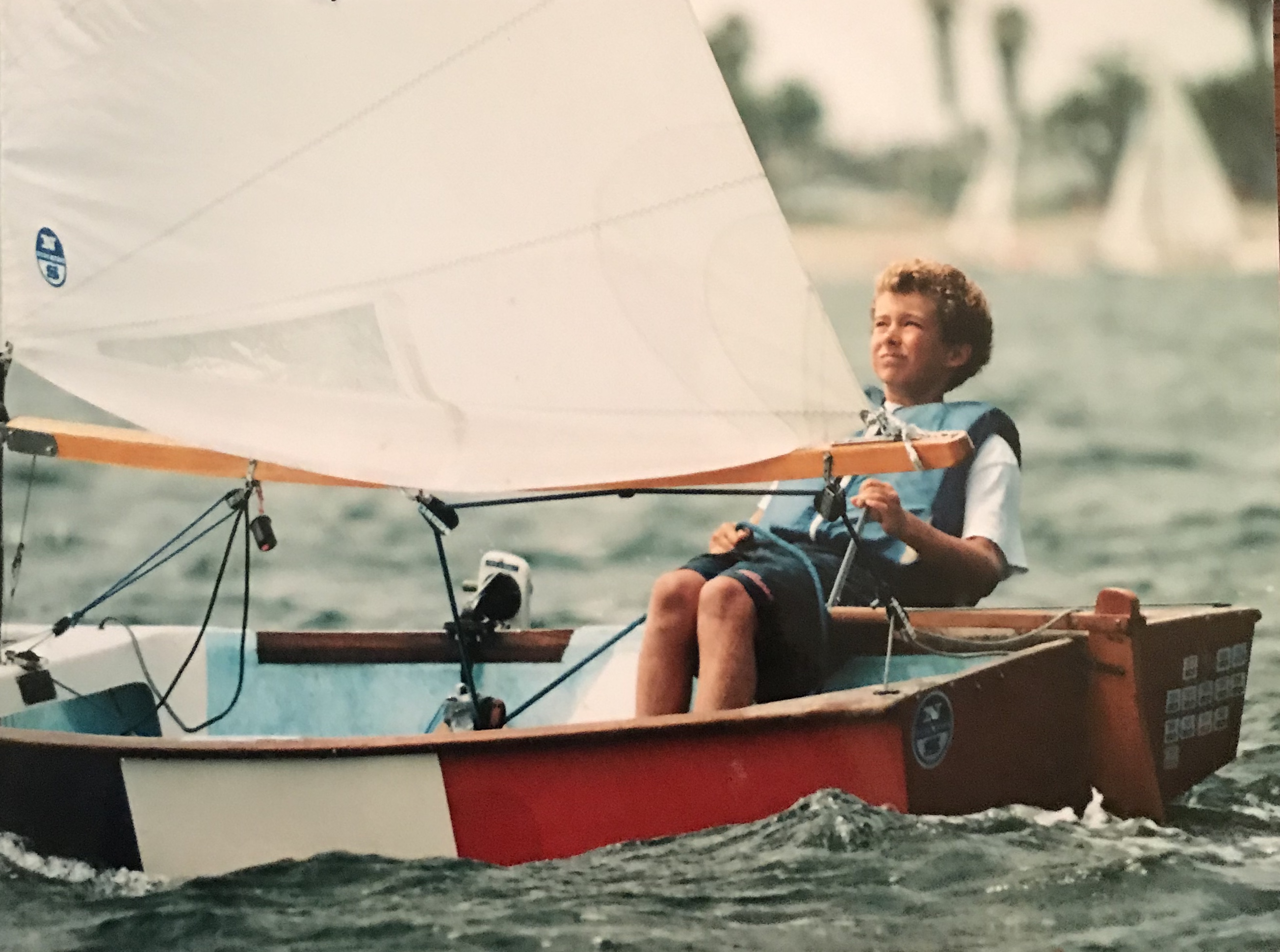 A young boy on a small sailboat. 