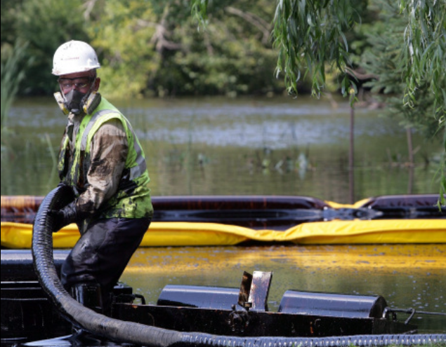 Spill responser pulls oiled boom into small boat.