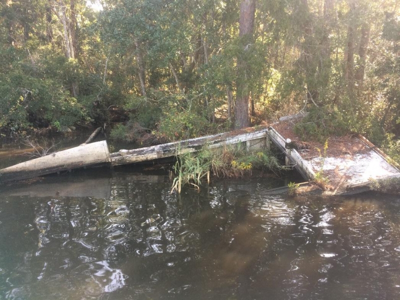 A damaged derelict vessel grounded on a shoreline.