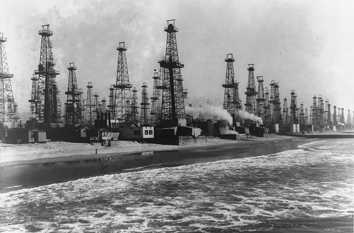 Black and white photo of dozens of oil derricks on the shore of Venice, California.
