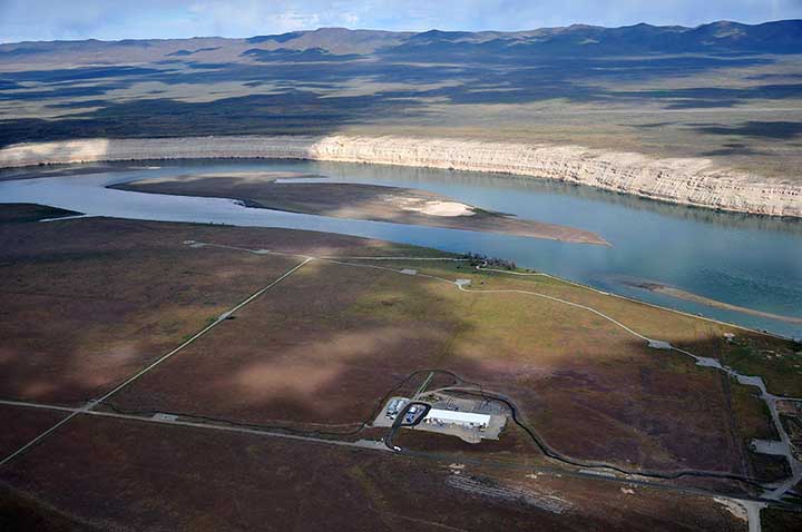 Roads and facilities of Hanford next to the Columbia River with bluffs and hills beyond.