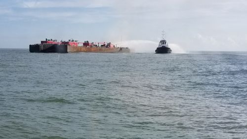 A vessel sprays water on the burning barge. 