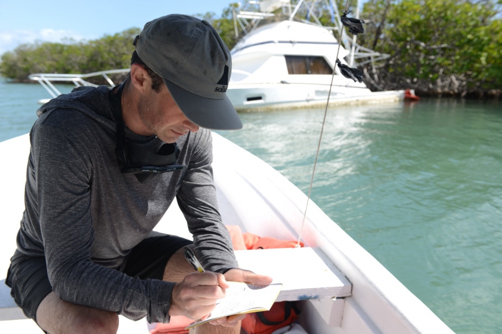 A man on a boat writing on a clipboard.