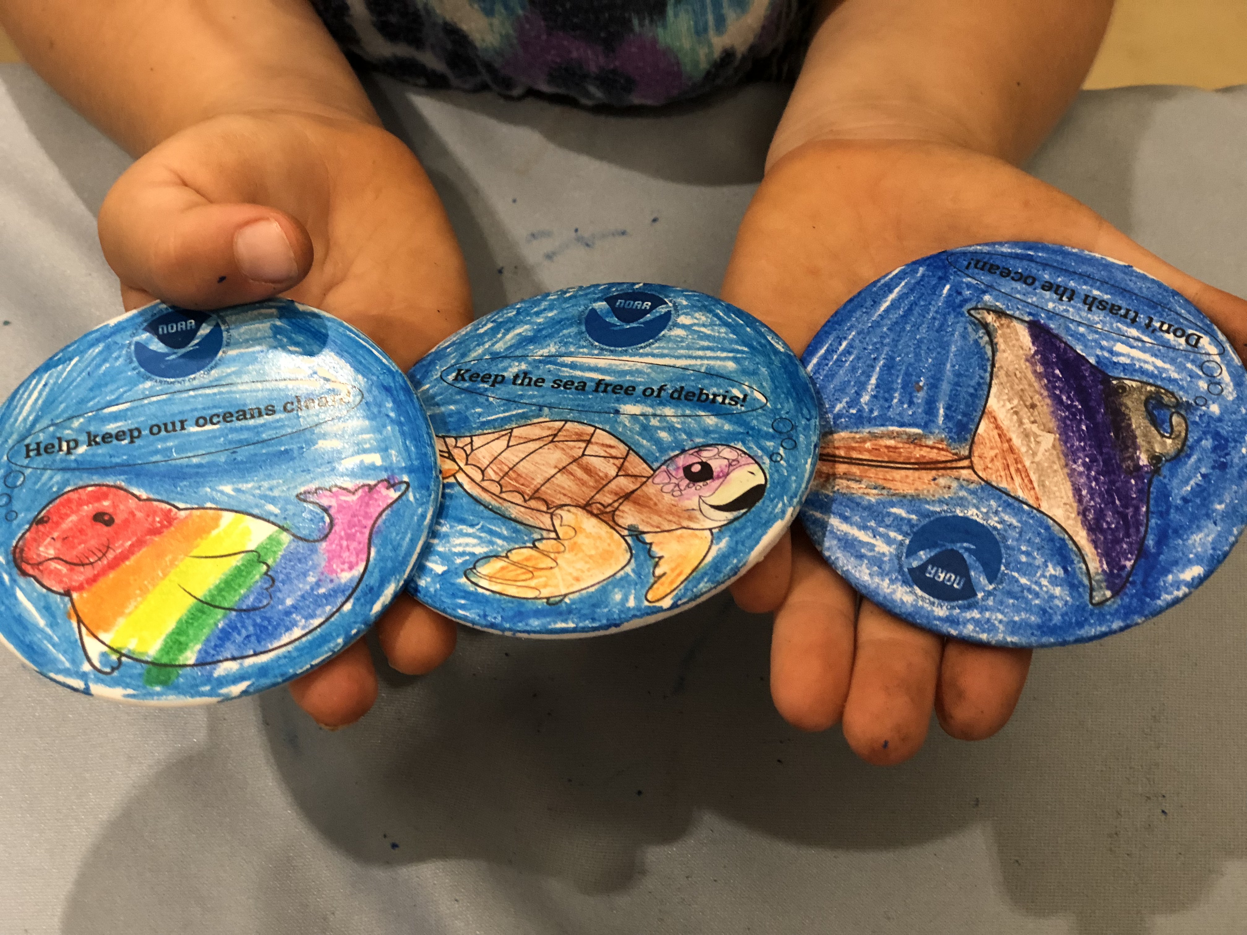 Hands holding three painted plates.