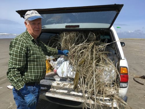 Man with debris standing by back of car. 