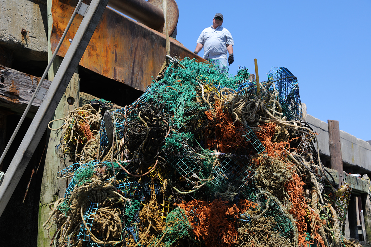 A large ball of marine fishing nets being pulled up to a dock. 