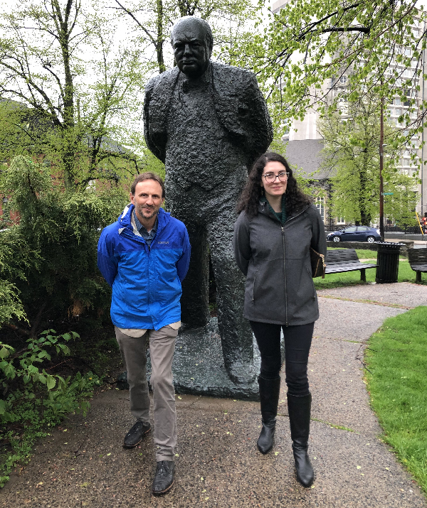 Two people posing for photo in front of a statue.