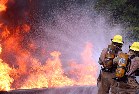 Two firefighters spraying water onto a fire.