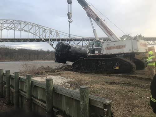 A crane towing a rail car from the river.