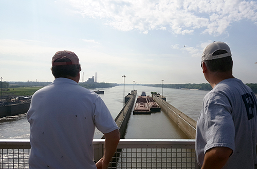 Two men on a boat looking at the water.