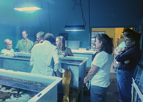 A group of people standing around a lab in discussion.