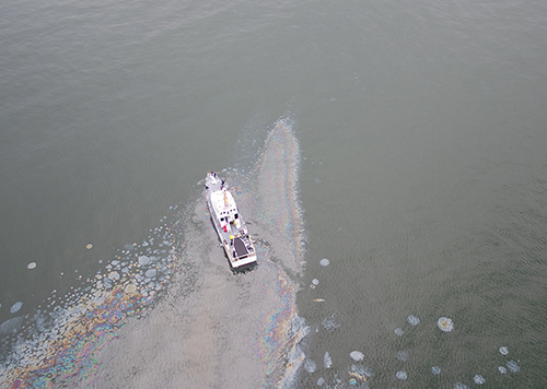 Aerial view of vessel on water in oil slick.