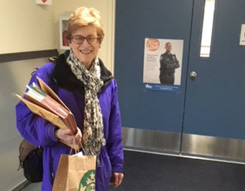 Woman smiling, holding books.