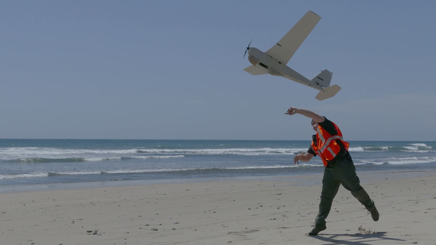 Man throwing what looks like a small airplane into the air.