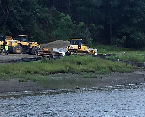 Heavy equipment operating on a riverbank.