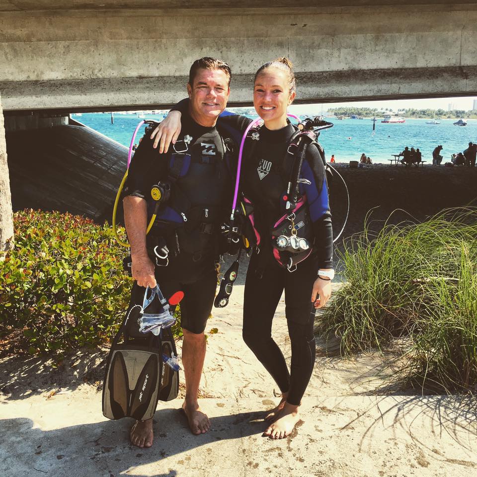 Two people in scuba diving gear posing for a photo. 