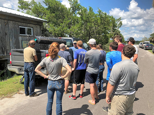 Group of people standing around a truck.