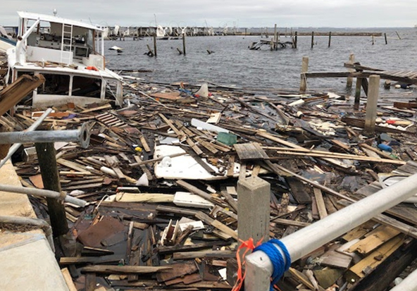 A vessel and a large pile of marine debris in the water next to a dock.