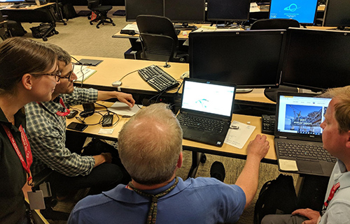 Four people gathered around computer monitor.