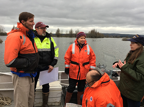 A group of people talking near water. 