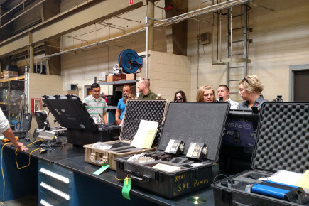 People standing around a table with cases and equipment.