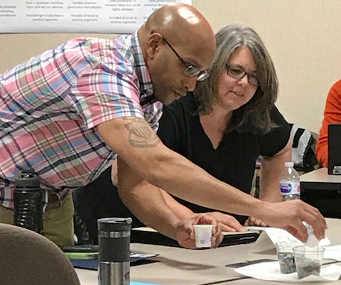 Man shows a woman something on a table. 