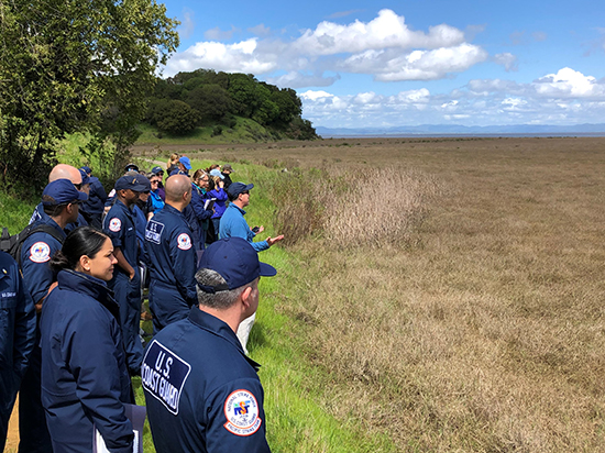 A group of people looking at an area of dry grass. 