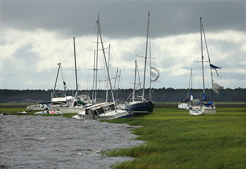 Sailboats askew by the edge of a marsh.