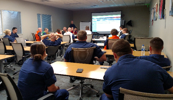 Participants listen to instructor at front of room.