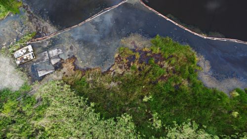 An aerial image of an oil sheen surrounded by pollution boom.