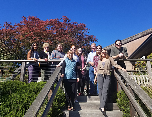 Group of people pose for photo outdoors around steps.