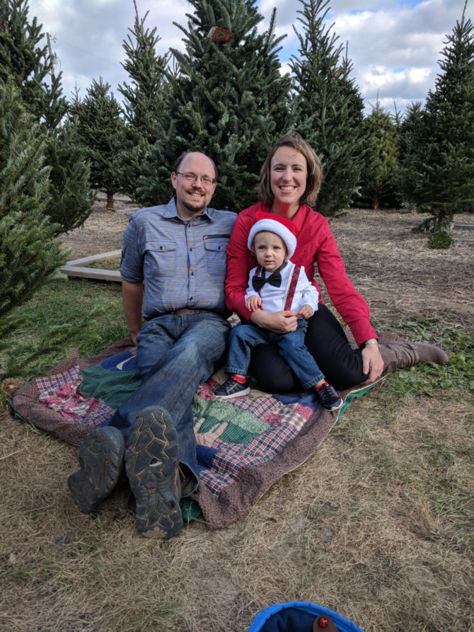 A man, child, and a woman pose for photo outdoors. 