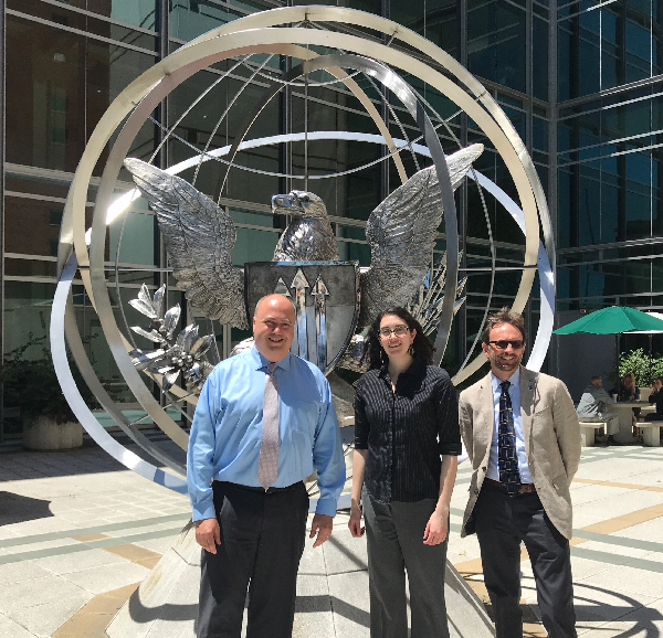 Three people pose in front of the Interagency Modeling and Atmospheric Assessment Center.