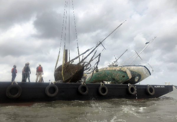 Sunken vessel being lifted from the water onto a boat.
